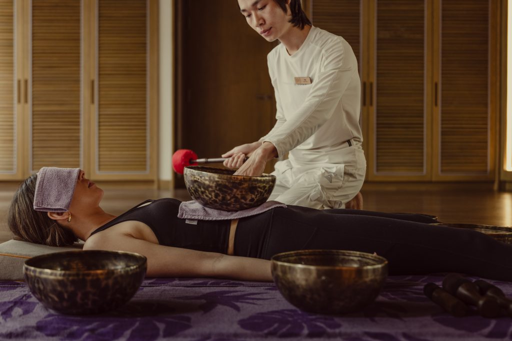 Wellness practitioner performing sound healing therapy with Tibetan singing bowls at luxury wellness resort in Da Nang, Vietnam
